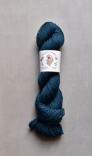 Load image into Gallery viewer, Blue skein of yarn with a label on a gray background