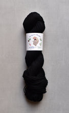 Load image into Gallery viewer, Black skein of yarn with a label on a gray background