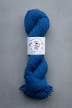 Load image into Gallery viewer, Blue skein of yarn with a label on a gray background