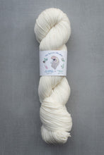 Load image into Gallery viewer, White skein of yarn with a label on a gray background