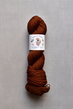 Load image into Gallery viewer, Brown skein of yarn with a label on a gray background