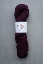 Load image into Gallery viewer, Burgundy skein of yarn with a label on a gray background