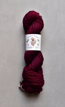 Load image into Gallery viewer, Burgundy skein of yarn with a label on a gray background