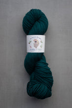 Load image into Gallery viewer, Teal skein of yarn with a label on a gray background