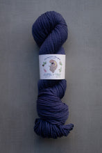 Load image into Gallery viewer, Navy skein of yarn with a label on a gray background