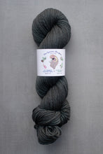 Load image into Gallery viewer, Gray skein of yarn with a label on a gray background