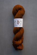 Load image into Gallery viewer, Brown skein of yarn with a label on a gray background
