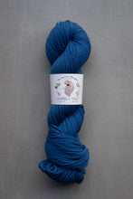 Load image into Gallery viewer, Blue skein of yarn with a label on a gray background