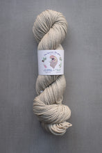 Load image into Gallery viewer, Beige skein of yarn with a label on a gray background