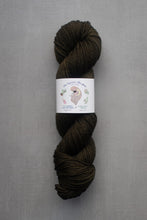 Load image into Gallery viewer, Dark brown skein of yarn with a label on a gray background