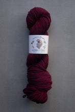 Load image into Gallery viewer, Burgundy skein of yarn with a label on a gray background