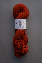 Load image into Gallery viewer, Ball of orange yarn with a label on a gray background