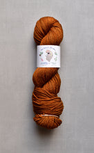 Load image into Gallery viewer, Brown skein of yarn with a label on a gray background