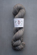 Load image into Gallery viewer, Gray skein of yarn with a label on a gray background