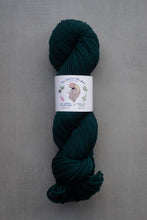 Load image into Gallery viewer, Dark green skein of yarn with a label on a gray background