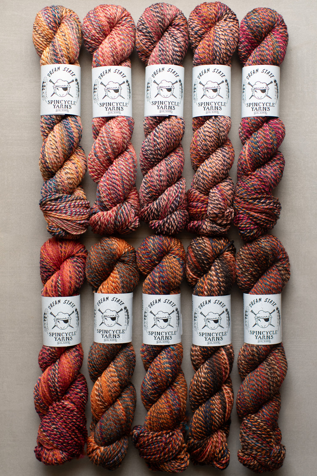 Set of six skeins of multicolored yarn with labels on a beige background