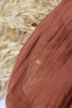 Load image into Gallery viewer, Close-up of a brown fabric with a logo, against a blurred straw background