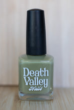 Load image into Gallery viewer, Green nail polish bottle with black cap on a wooden surface