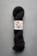 Load image into Gallery viewer, A single skein of dark charcoal gray yarn with a white paper label featuring a sheep illustration and the brand name set against a neutral gray background.