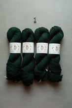 Load image into Gallery viewer, Four skeins of dark forest green yarn with white paper labels, arranged side by side on a neutral gray background with a small metal '1' above them.
