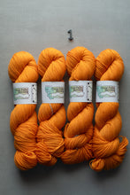 Load image into Gallery viewer, Four skeins of orange yarn with labels on a gray background