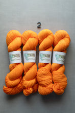 Load image into Gallery viewer, Four skeins of orange yarn with labels on a gray background