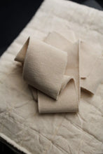 Load image into Gallery viewer, Folded beige fabric on a textured surface