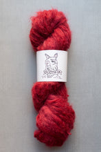 Load image into Gallery viewer, Red skein of yarn with a label on a gray background