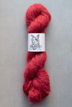 Load image into Gallery viewer, Red skein of yarn with a label on a gray background