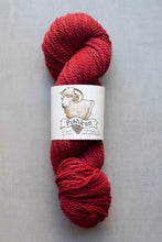 Load image into Gallery viewer, Red skein of yarn with a label on a gray background