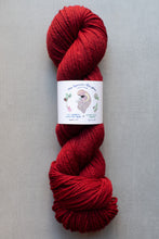 Load image into Gallery viewer, Red skein of yarn with a label on a gray background