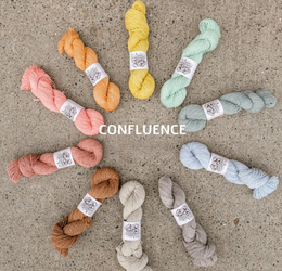 Set of colorful yarn skeins arranged in a circle on a concrete surface with 'Confluence' branding.
