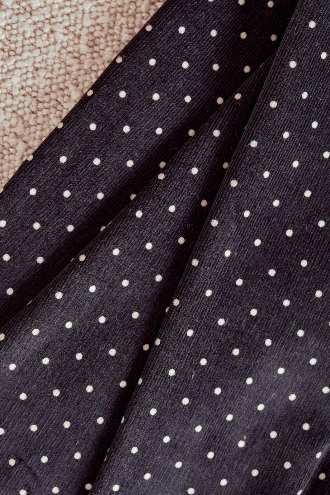 Close-up of black fabric with white polka dots on a textured surface