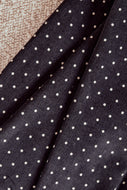 Close-up of black fabric with white polka dots on a textured surface