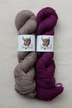 Load image into Gallery viewer, Two skeins of yarn side by side on a light beige textured background. The left skein is a muted taupe-gray, and the right skein is a deep plum-purple.