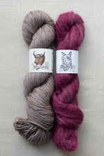 Load image into Gallery viewer, Two skeins of yarn laid side by side on a light beige textured background. The left skein is a soft taupe-gray, and the right skein is a rich magenta-purple.