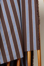 Load image into Gallery viewer, Brown and blue striped fabric draped over a wooden chair.