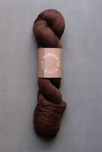 Load image into Gallery viewer, Brown skein of yarn with a label on a gray background