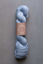 Load image into Gallery viewer, Blue skein of yarn with a brown label on a gray background