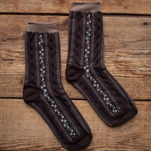 Load image into Gallery viewer, Pair of brown socks with decorative patterns on a wooden surface