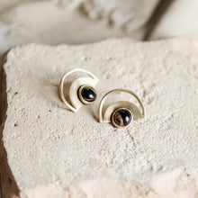 Load image into Gallery viewer, Pair of earrings with half-circle design and black gemstones on a textured surface