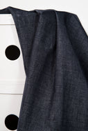 Dark blue fabric draped over a white surface with black circular patterns.