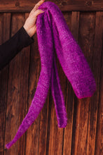 Load image into Gallery viewer, Purple knitted scarf held by a hand against a wooden background