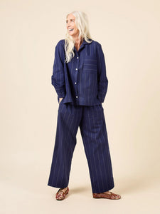 Woman wearing a navy pinstripe suit against a beige background