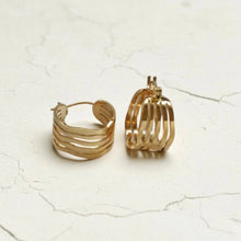 Load image into Gallery viewer, Gold hoop earrings on a light textured surface