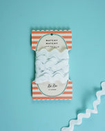 Packaged ribbon with striped design on a light blue background