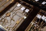 Gold jewelry on display with tags in a glass case.