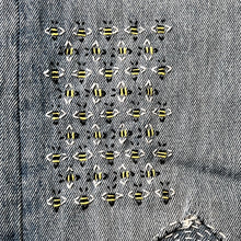 Load image into Gallery viewer, Close-up of a textured fabric surface with small decorative elements.