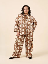 Load image into Gallery viewer, Person wearing a brown and white geometric patterned outfit on a beige background