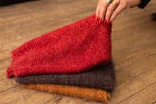 Load image into Gallery viewer, Stack of red, brown, and orange textured cloths on a wooden surface.